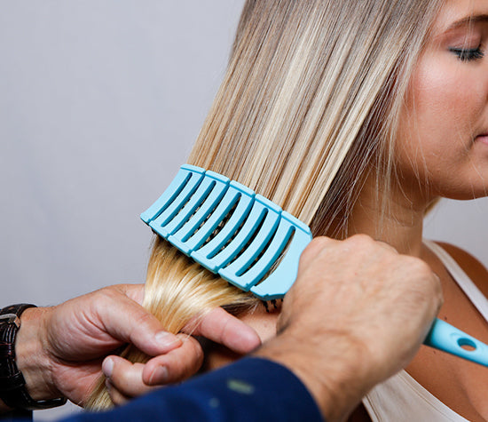 Hairdresser using the blue Flex Brush to detangle a client's hair