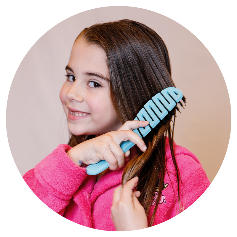 A little girl using a Flex Brush to brush her hair